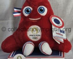 Paris 2024 mascotte Phryge hauteur 28 cm, fabrication française par Doudou et Compagnie. La Phryge est un personnage inspiré du bonnet phrygien, qui représente un grand symbole de liberté, d’inclusivité et la capacité du monde à soutenir de grandes causes. Elle arbore du bleu, du blanc et du rouge ainsi que le logo doré de Paris 2024 sur sa poitrine. Ses yeux ont été pensés pour être à la fois malicieux et expressifs, et dessinent une cocarde afin que le bonnet phrygien soit immédiatement identifiable. Elle a été conçue par l'agence W, notamment Gilles Deleris, cofondateur de l'agence, et les équipes de design de Paris 2024, dont le directeur artistique est Joachim Roncin en collaboration avec Jules Dubost et Gilles Deléris.